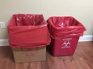 Red Bag Setup A cardboard box and a plastic bin, both lined with red biohazard bags and marked with biohazard symbols.
