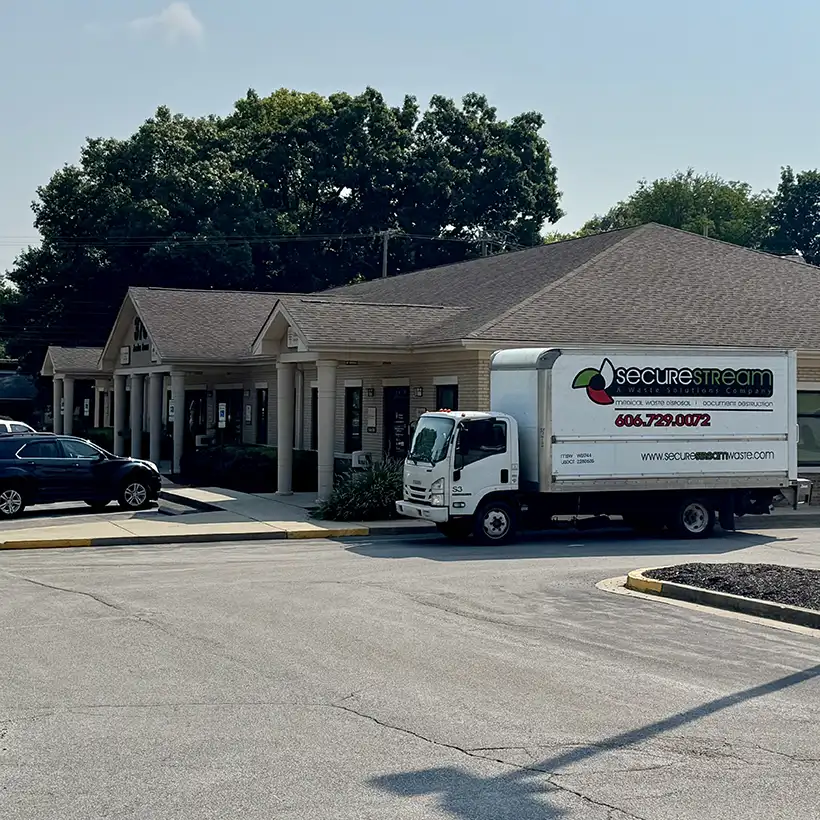 A SecureStream medical waste truck parked in front of a one-story commercial building.