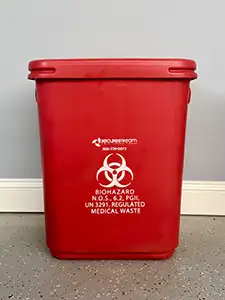 Medical Waste & Sharps Disposal Red biohazard waste container with a lid, labeled for regulated medical waste.