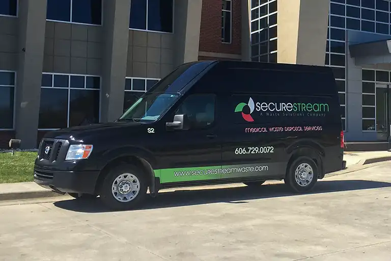 Black SecureStream medical waste disposal van parked in front of a building.